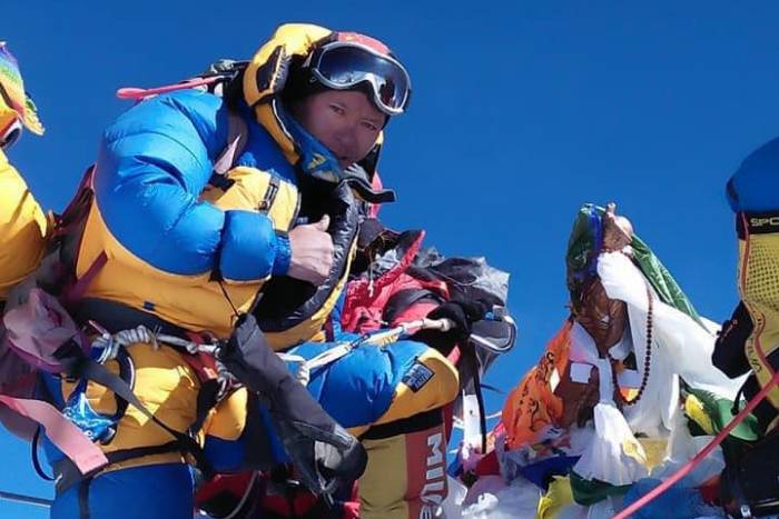 The Sherpa climbers with a thumbs-up on a Himalayan summit, probably Everest, on a bluebird day.