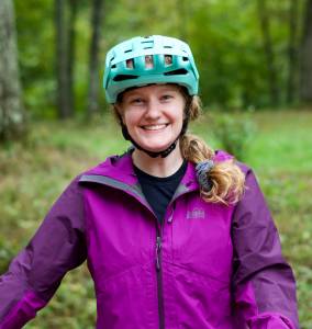 Portrait of GearJunkie team member Katie Eichelberger wearing a purple rain jacket and blue helmet