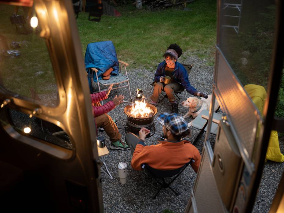 Need Inspiration for Adventurous Gifts? Explore REI’s Gift Center people sitting around a campfire while camping.