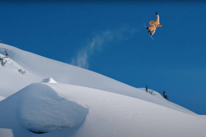 a snowboarder catches huge air against a blue sky in a screenshot from the ARK trailer