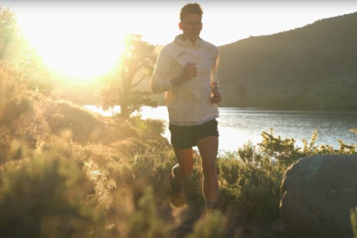 ultra runner tim tollefson runs along a river with a sunrise behind him
