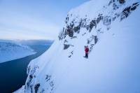 Surf, Snowboard, Synth: Film Explores Human Creativity Through Sport and Music person in Iceland with a snowboard on the edge of a snowy mountain cliff