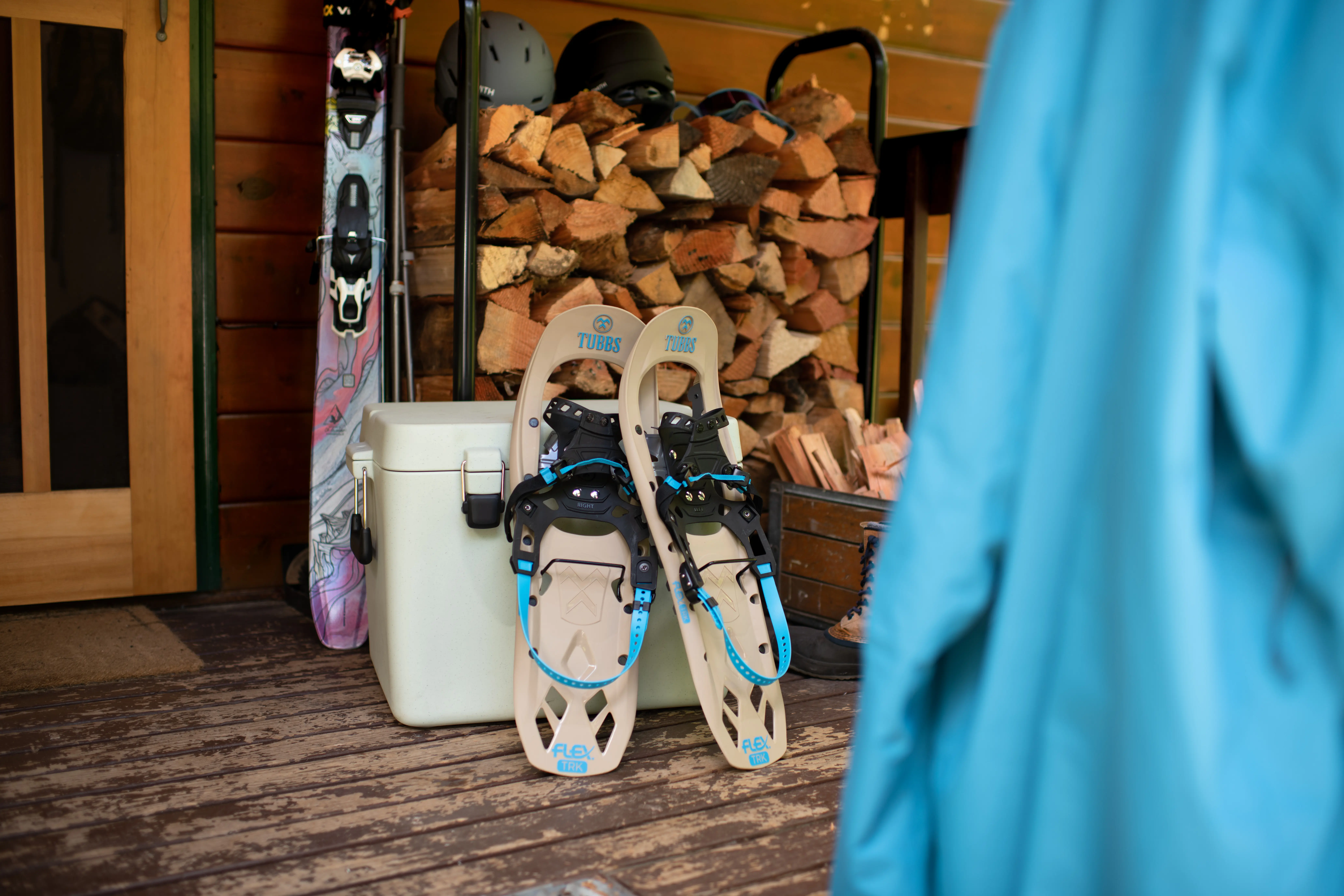 snowshoes sitting next to a cooler with skis and a woodpile in the background snowshoes sitting next to a cooler with skis and a woodpile in the background
