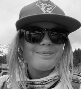 author Claire Barber in a hat, sunglasses, and overalls