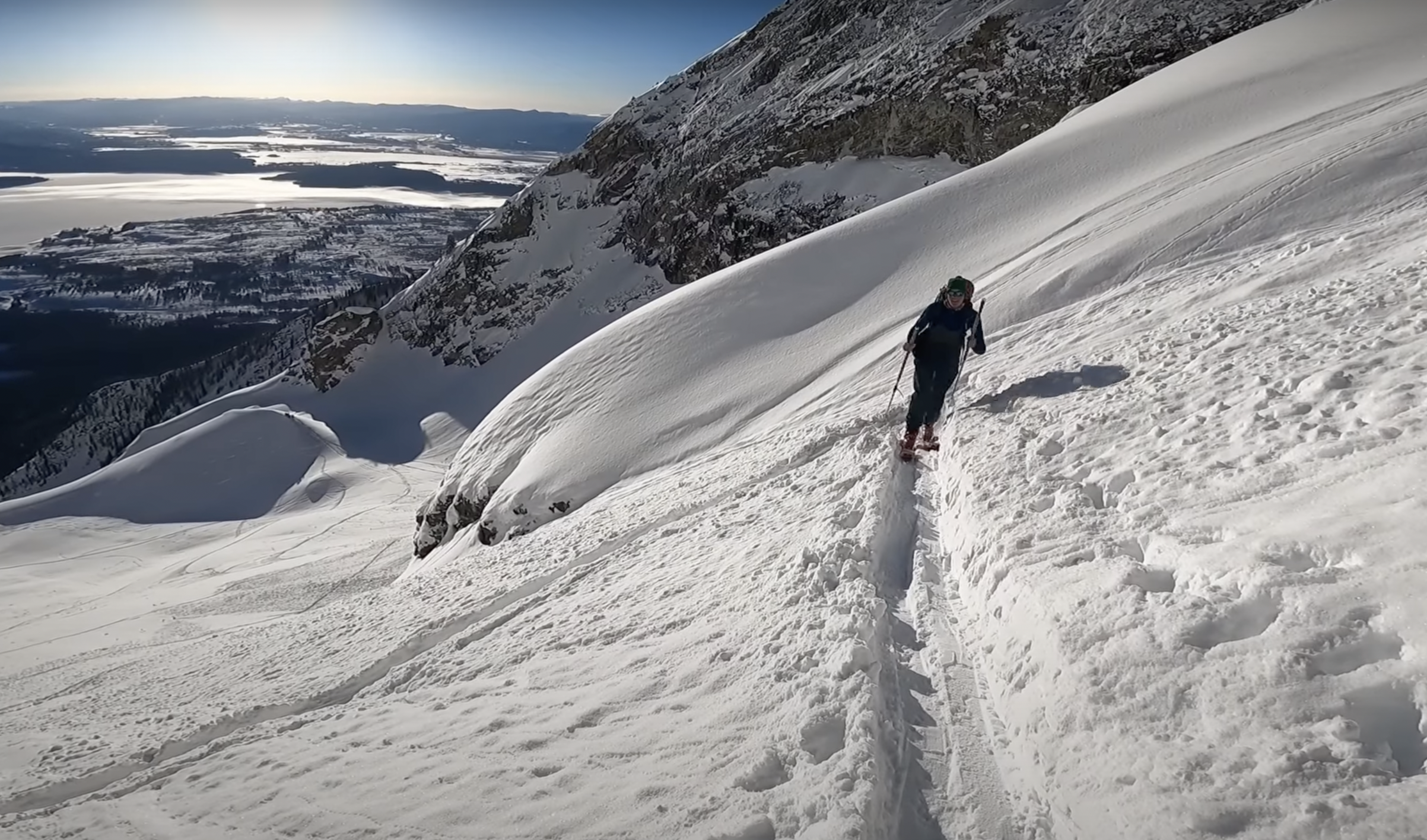 A skier ascends a snowy slope in the Teton range