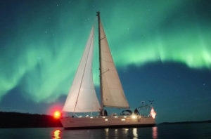 A sailboat in Norwegian seas against the Northern Lights