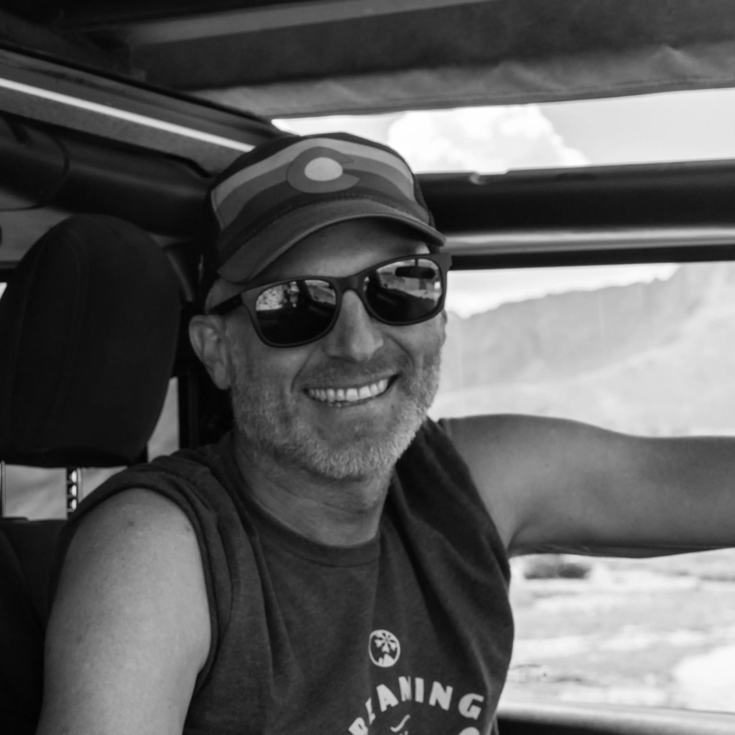 cam martindell wearing a hat and sunglasses and tank top and smiling