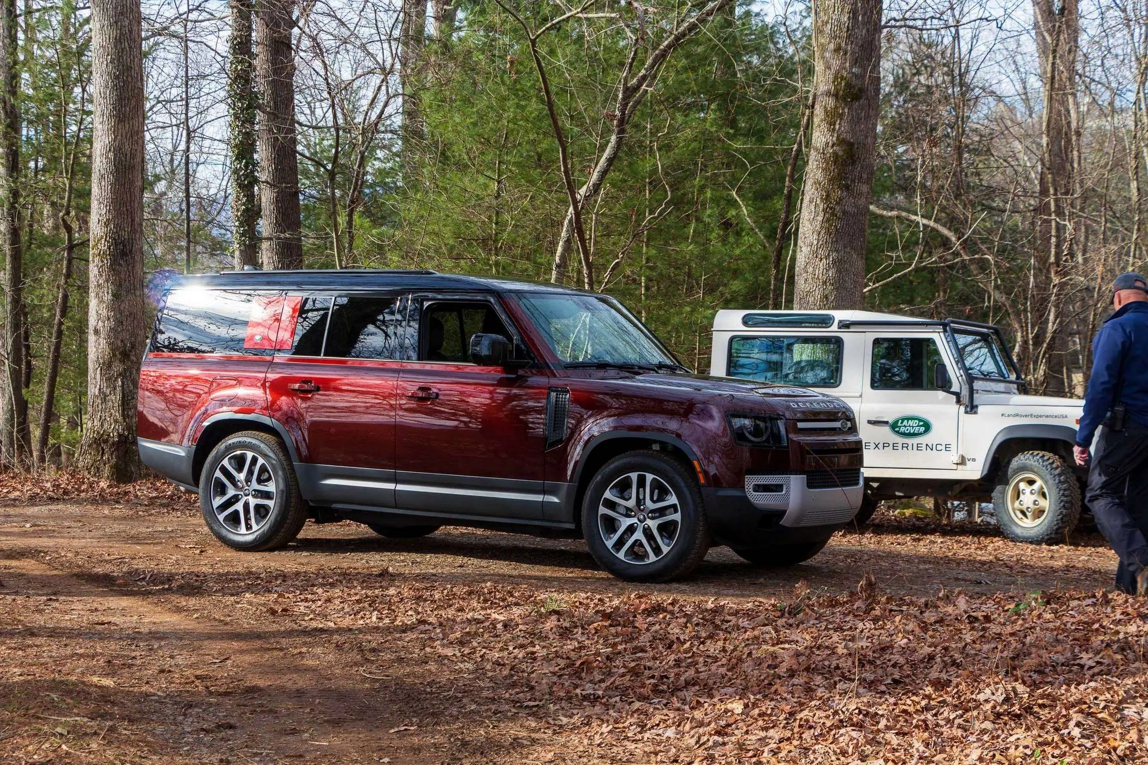Land Rover Defender 130 Review side view on dirt trail next to older model.