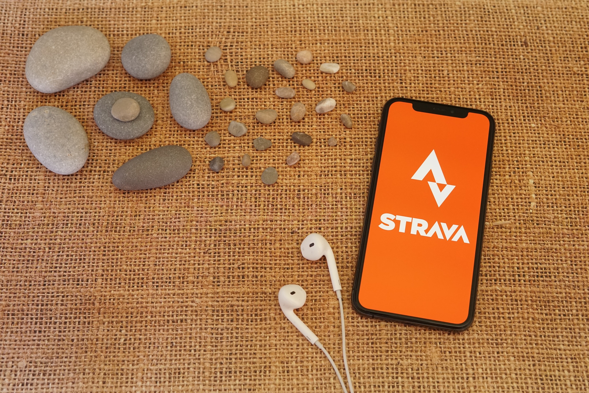 the strava logo displayed on a phone, with headphones