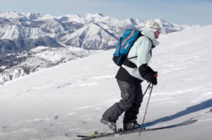 a telemark skier skins up a snowy slope
