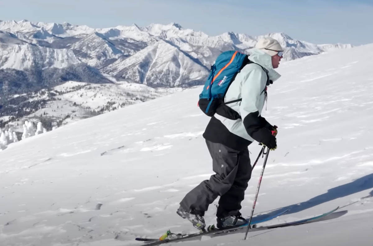a telemark skier skins up a snowy slope