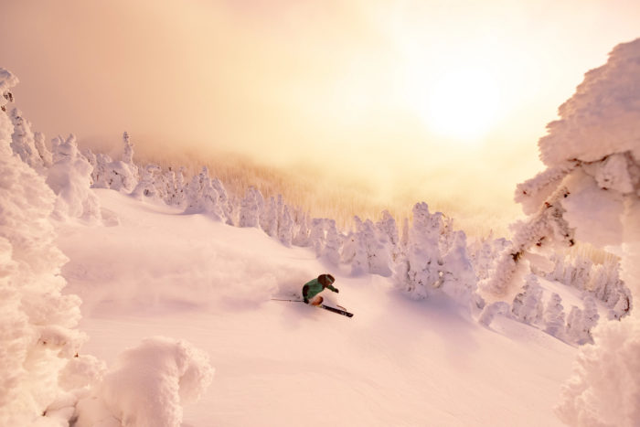 Person snowboarding surrounded by a bright sun and tons of snow