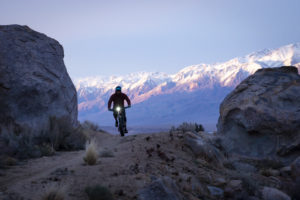 Riding on a gravel road with a bike light with snow-capped mountains in the background