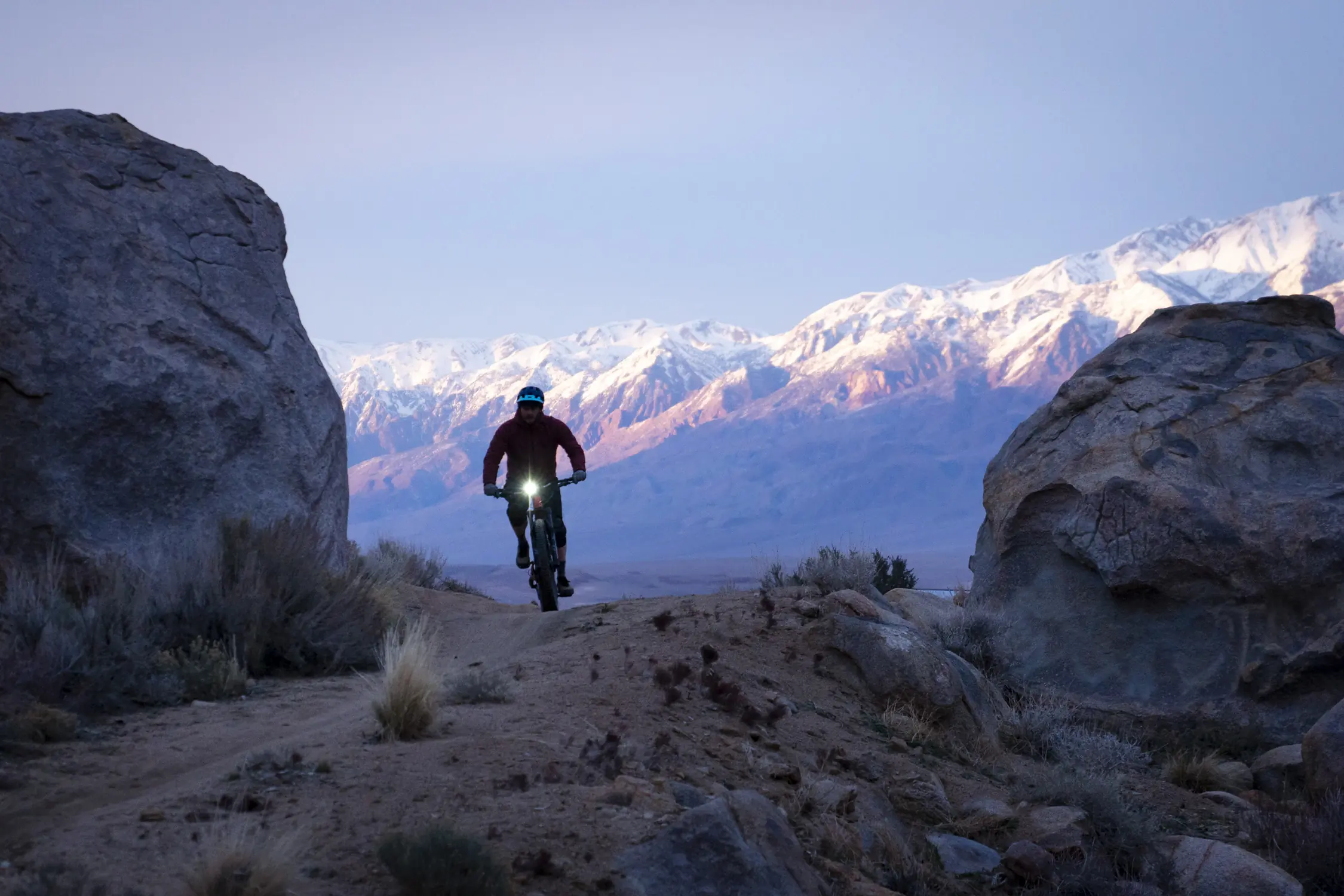 Riding on a gravel road with a bike light with snow-capped mountains in the background