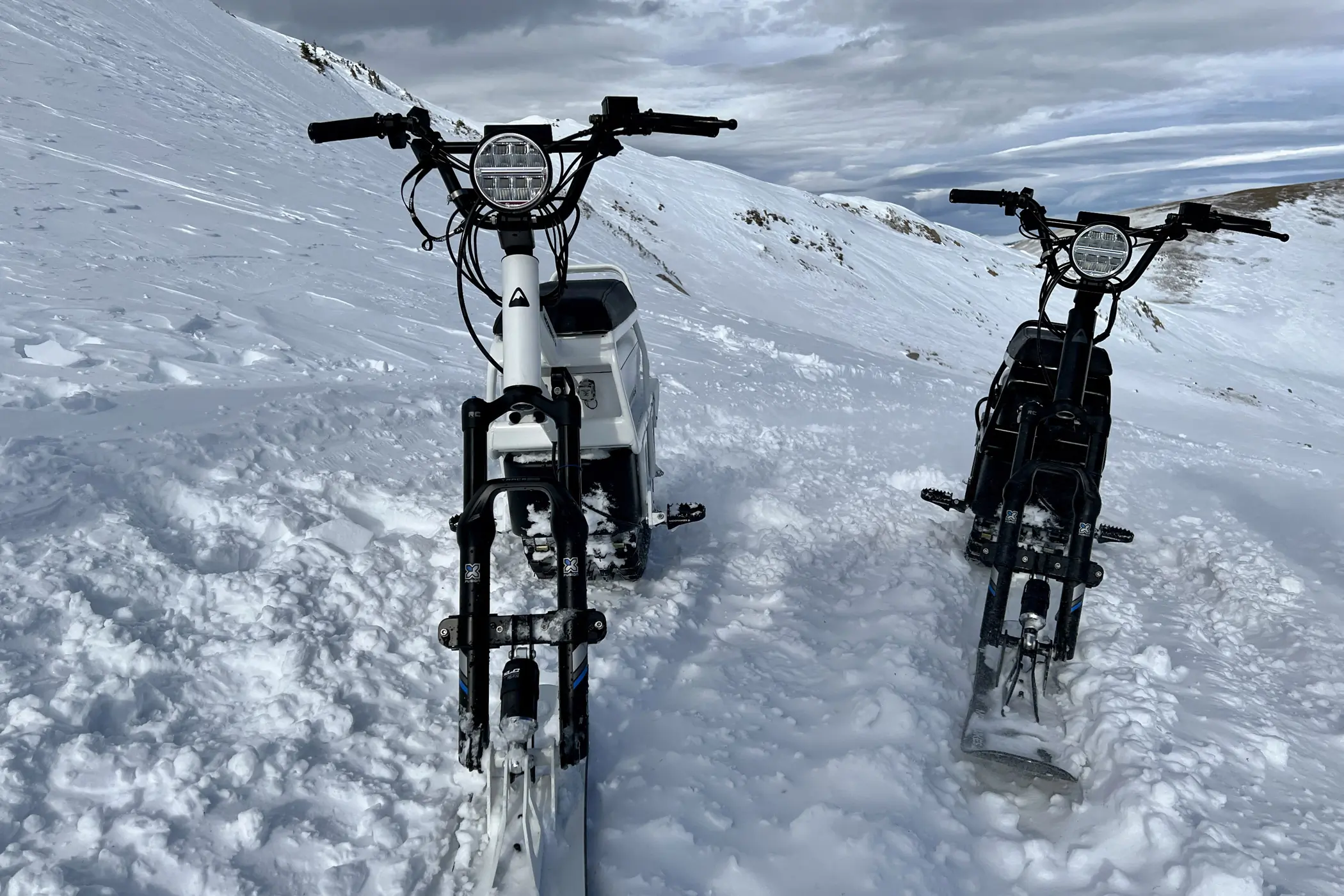 Two MoonBikes side by side, front view, on snow.