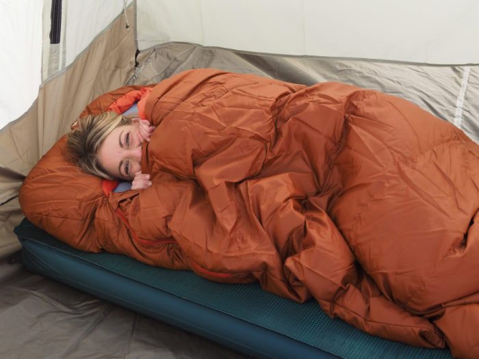 woman in the REI Hunkerdown 20 sleeping bag on top of the Nemo Roamer sleeping pad.