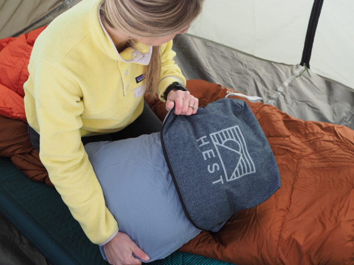 A woman pulling a Hest Pillow out of it's case for sleeping.