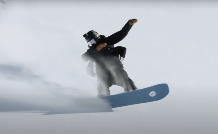 A snowboarder carving powder
