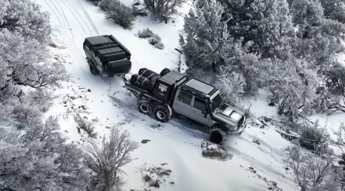 A six-wheel-drive Toyota Land Cruiser towing a trailer through snow