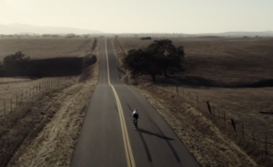 a cyclist pedals down a lonely highway