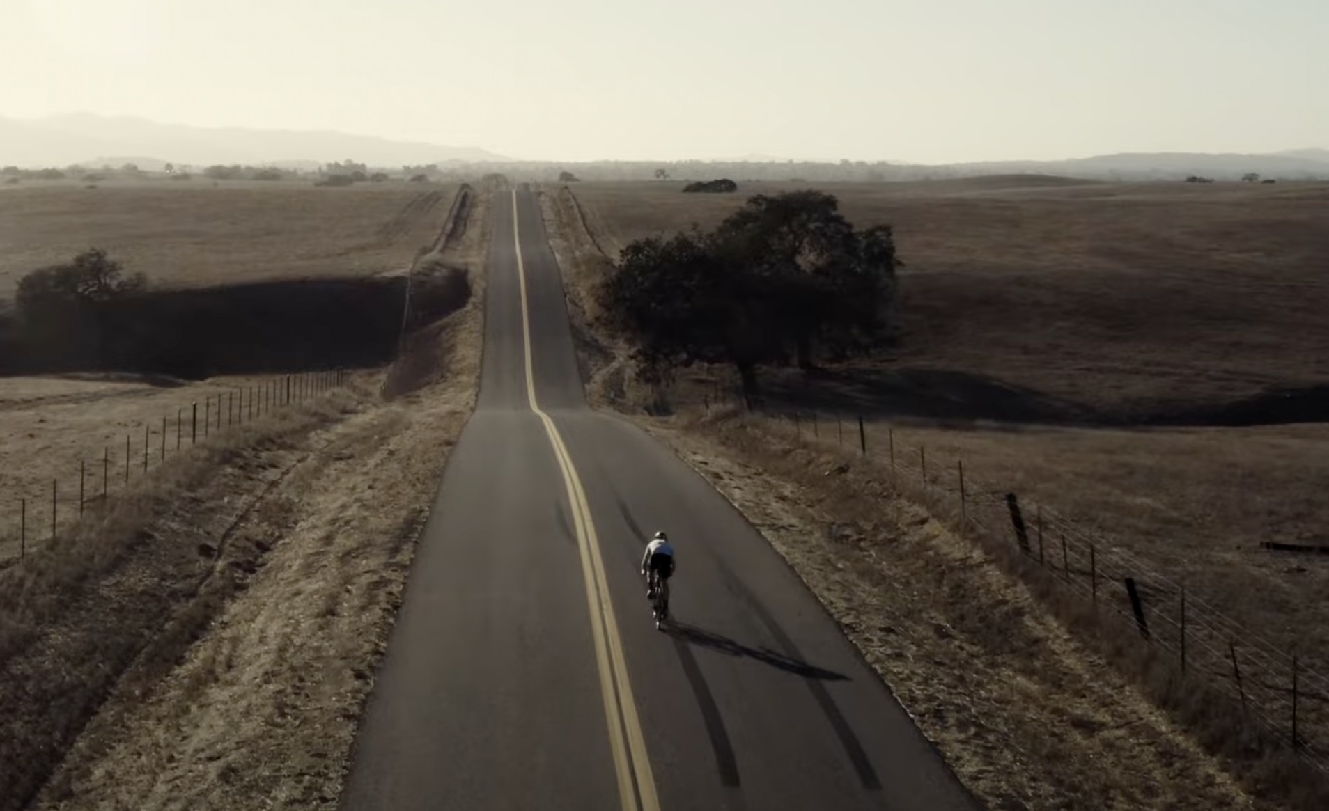 a cyclist pedals down a lonely highway