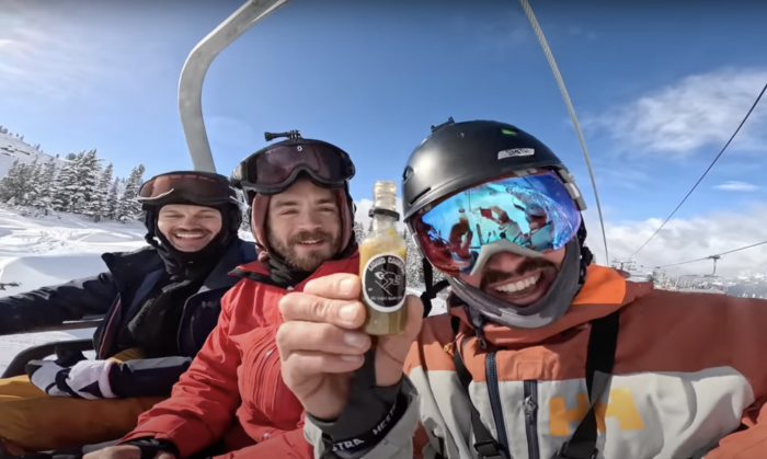 skiers on a chairlift with a bottle of hot sauce