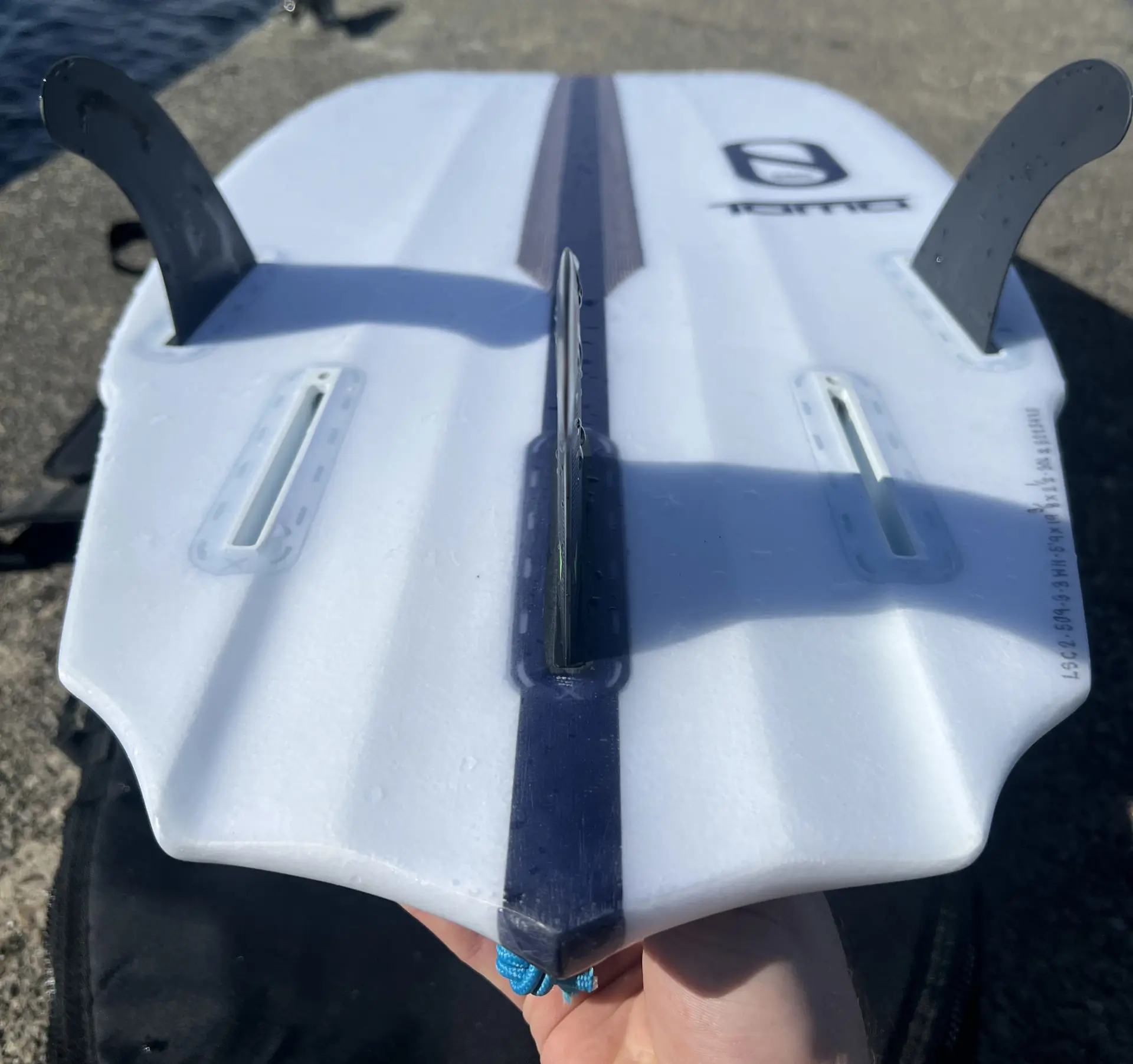 Slater Designs Sci-Fi 2.0 surfboard underside showing three fins lying on dock