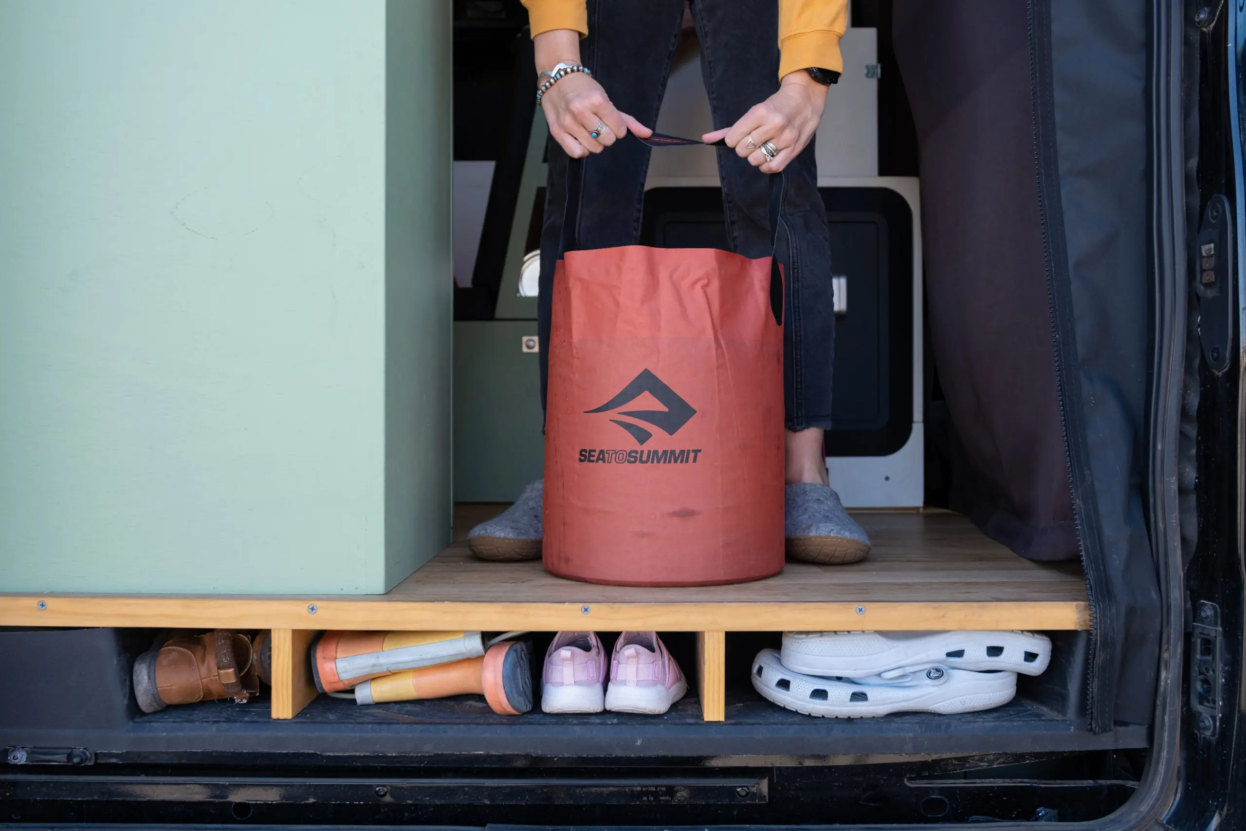 Woman Holding a Sea to Summit Collapsible 5-Gallon Bucket in a Campervan Favorite Van Life Gear