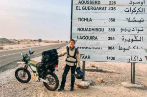 Woman with electric motorcycle on a deserted road