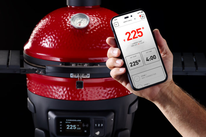 a red ceramic grill with a hand holding a phone in front of it