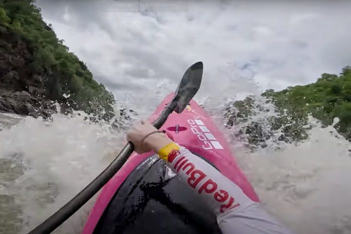 POV image of pink boat kayaking through heavy rapids