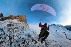 a paraglider lands on a snowy slope