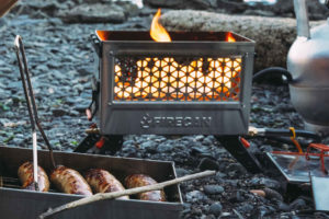 brats cooking in firecan deluxe on rocky beach