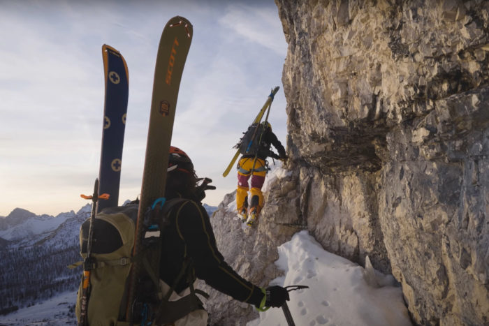 two ski mountaineers navigate a tricky ledge