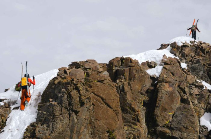 Two skiers on a snowy summit ridge