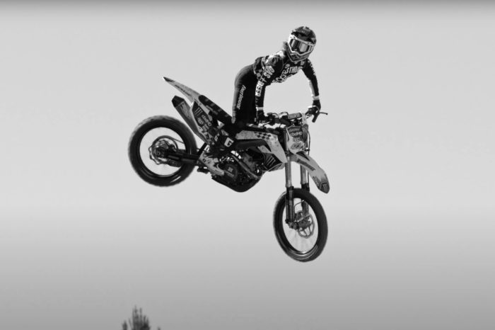 a woman on a dirt bike going over a huge jump, shot in black and white