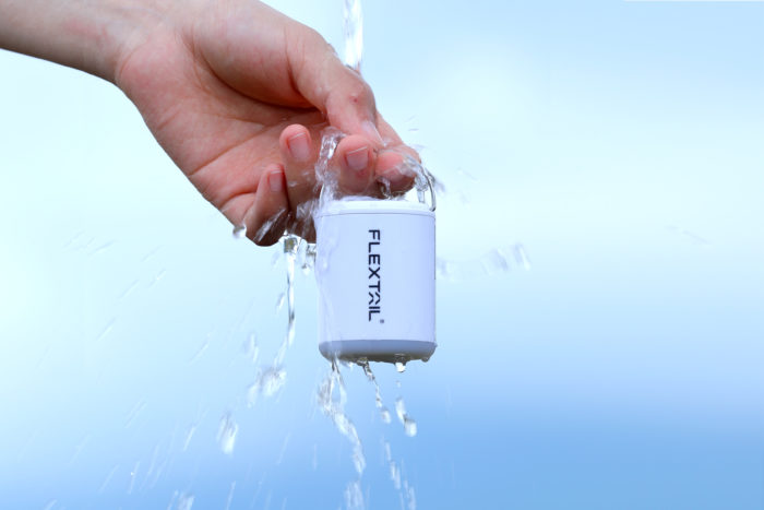 FLEXTAIL TINY PUMP 2X with water splashing on it while someone holds it