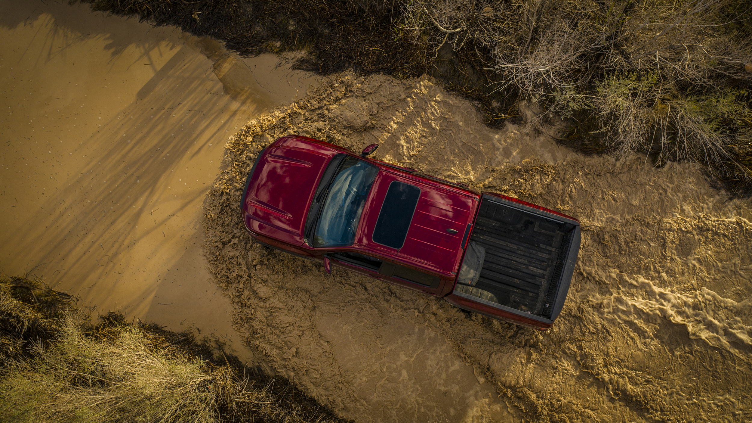 drone shot of 2023 nissan frontier crossing a river