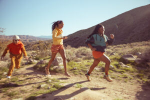 Three people trail running through some dirt wearing REI's Trailmade collection