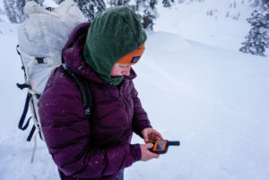 A Hiker Holds The SPOT X Messenger While Navigating in Snow