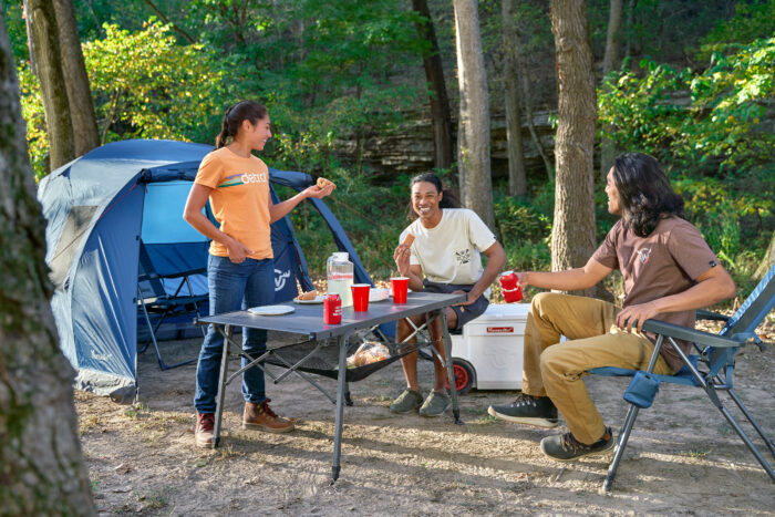 three people sitting around a campsite using Moosejaw Comfort Camp gear