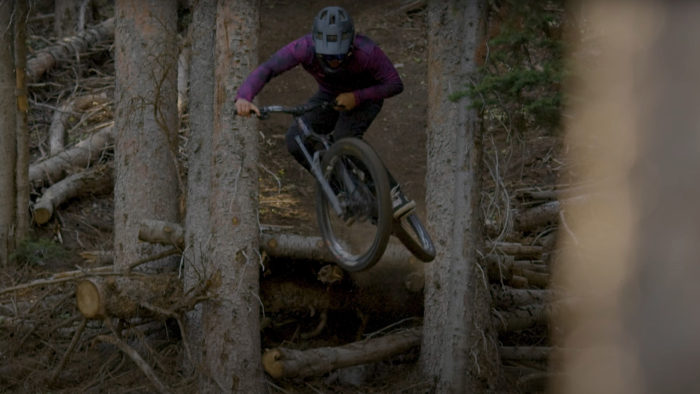 a rider in a purple jersey jumps some logs