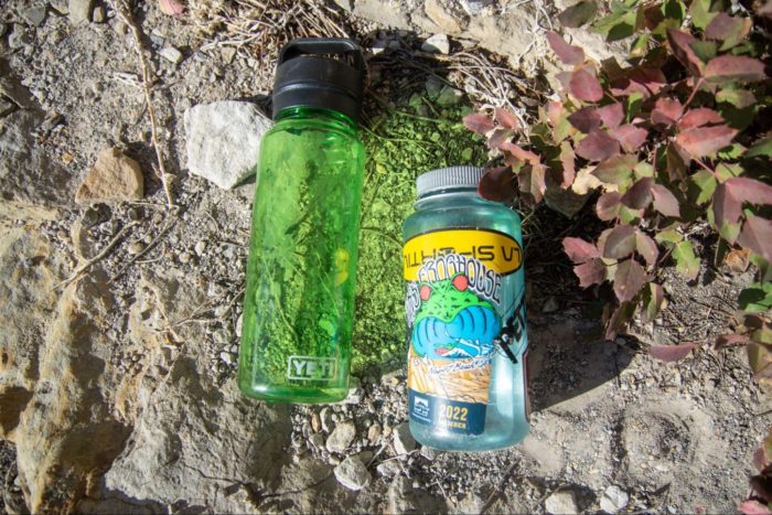 yeti yonder water bottle laying next to nalgene near rocks