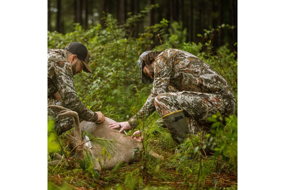 hunters crouching over a deer harvest