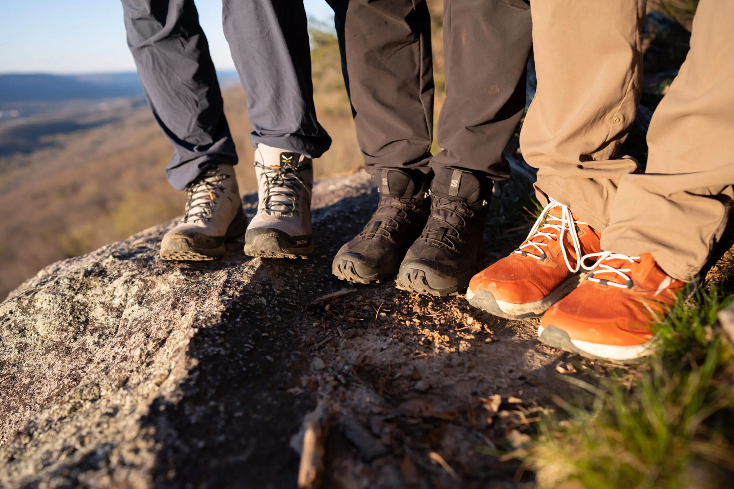 Professional hiking boots displayed on rocky terrain showing various models suitable for long distance walking