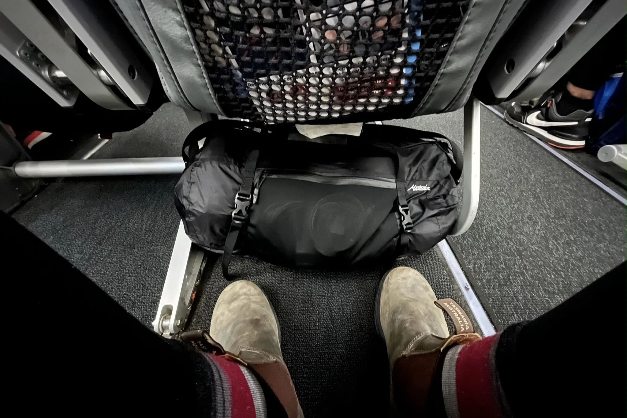 Duffel bags under seat in plane as carry-on.