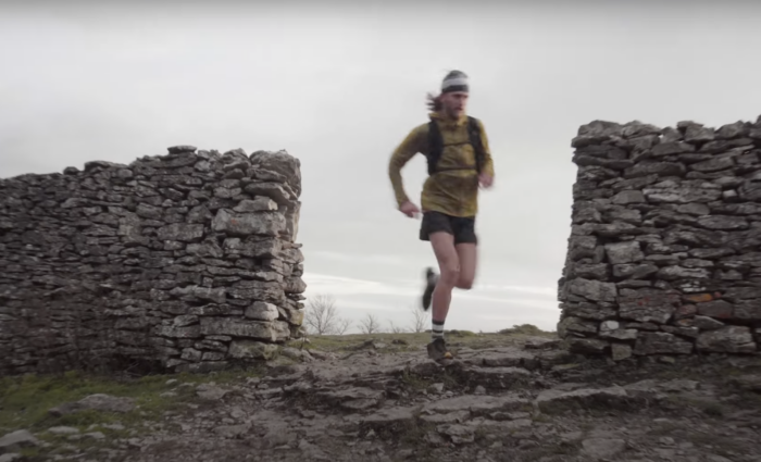 kyle richardson running through an opening in a stone wall in the lake district