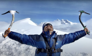 hari budha magar celebrates with two ice axes held wide