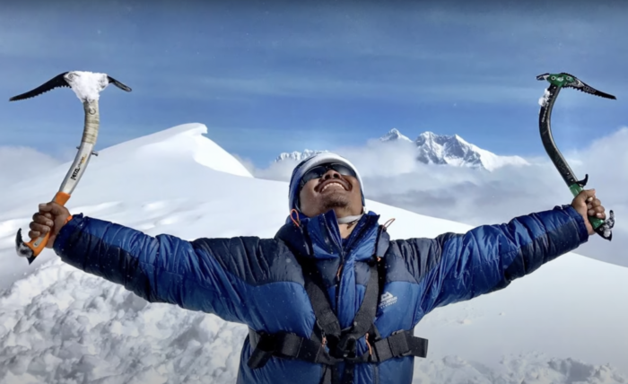 hari budha magar celebrates with two ice axes held wide