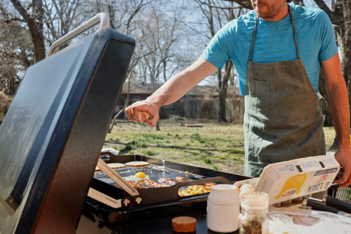 Man cracking eggs on traeger flatrock propane grill